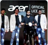 Four men standing around a motorcycle with Acer official licensee banner behind