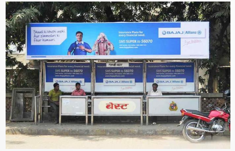 Bus shelter with billboard and motorbike parked nearby under blue sky