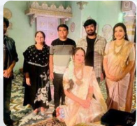 Group photo of seven people standing and sitting indoors, some in traditional attire