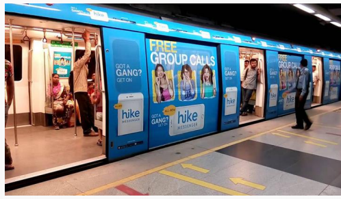 Metro train with blue advertisements on side and people on platform