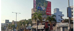 Man in blue shirt standing with a red billboard behind him